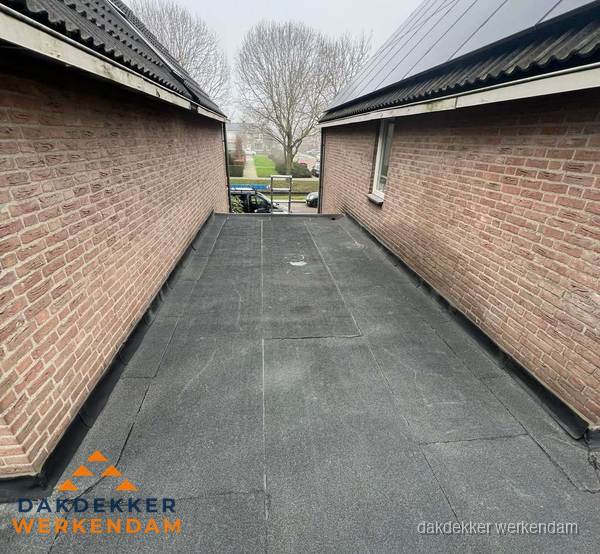 Plat dak met bitumen dakbedekking tussen bakstenen muren in Werkendam Plat dak met bitumen dakbedekking tussen bakstenen muren in Werkendam